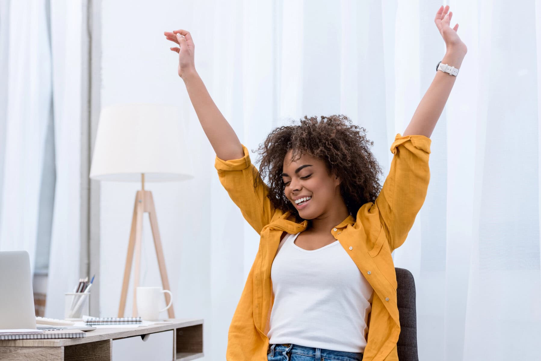 Relaxed woman stretching at her desk, enjoying a moment of wellness and rejuvenation.
