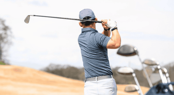 Golf player preparing to swing on the course A golfer in a blue shirt and cap preparing to hit a shot on the golf course.